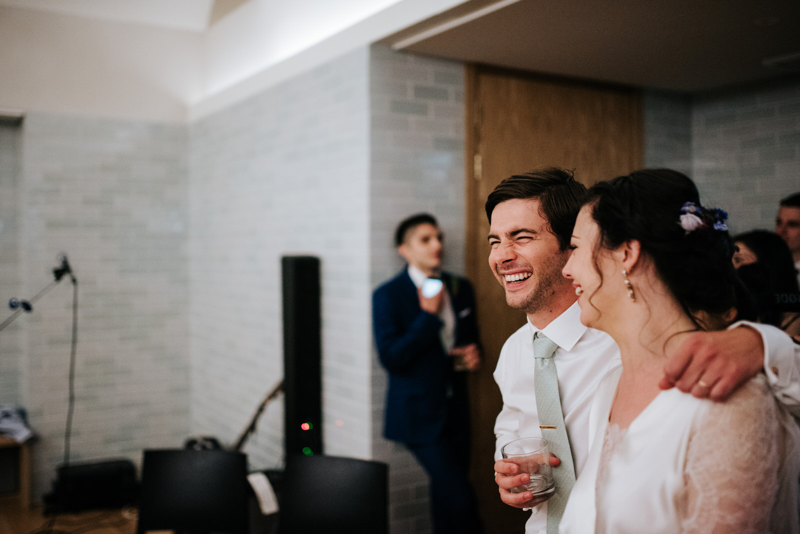 Groom reacts to speeches by squeezing bride and smiling 