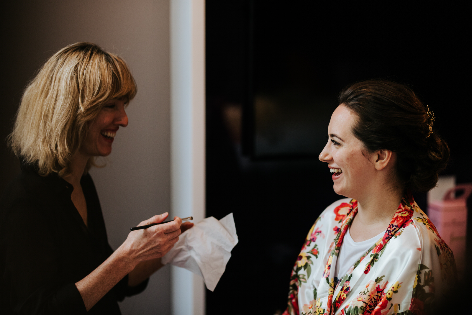 Bride smiles in robes as make-up artist begins working