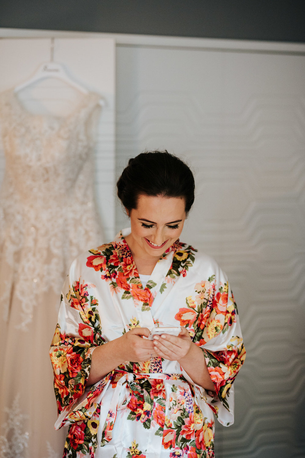 Bride looks and smiles at phone as she reads a text message