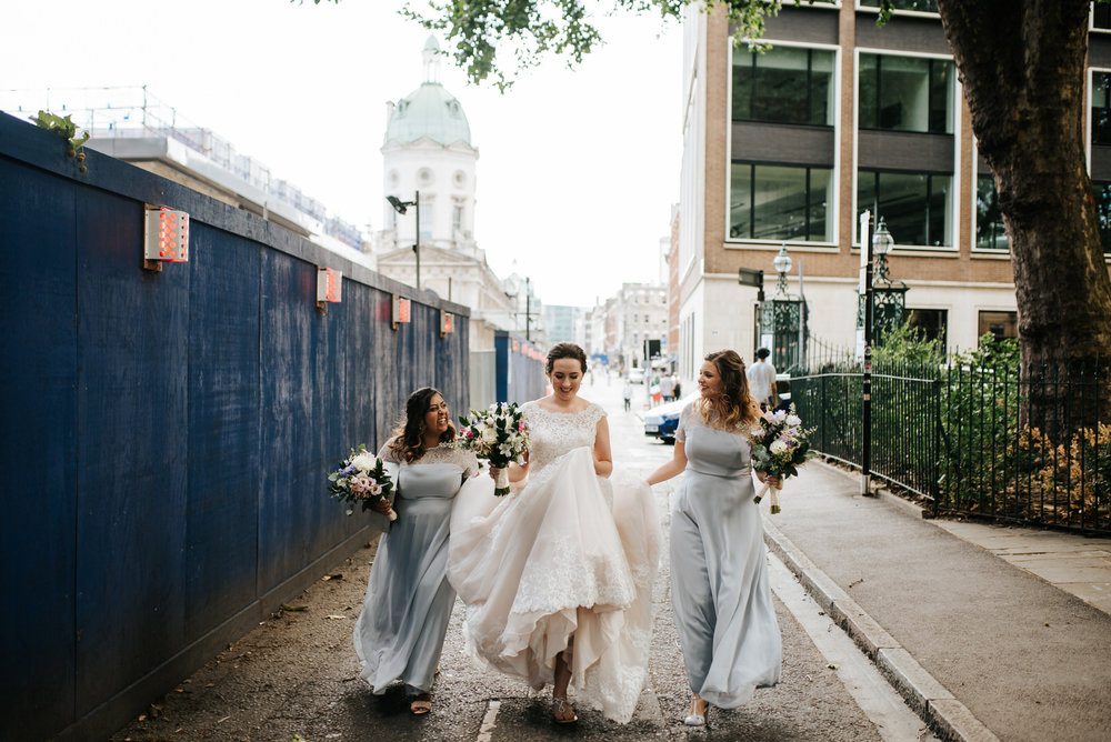 Bride and bridesmaids walk on the streets of London as they hold
