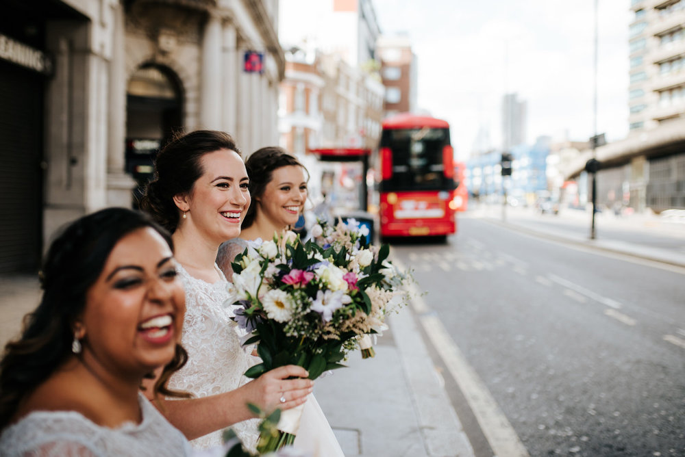 Bride and bridesmaids wait to cross the road in London to arrive