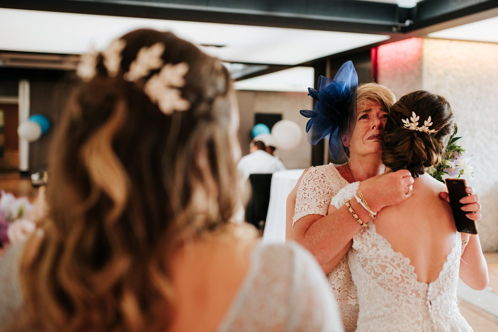 Family member embraces the bride as tears flow down her face