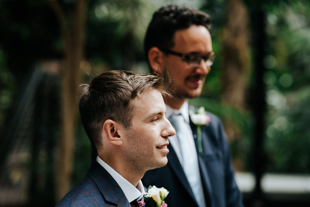 Groom and his best man wait at the front of the aisle