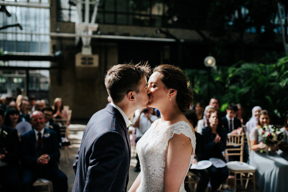 Bride and groom share their first kiss in beautiful, dappled lig