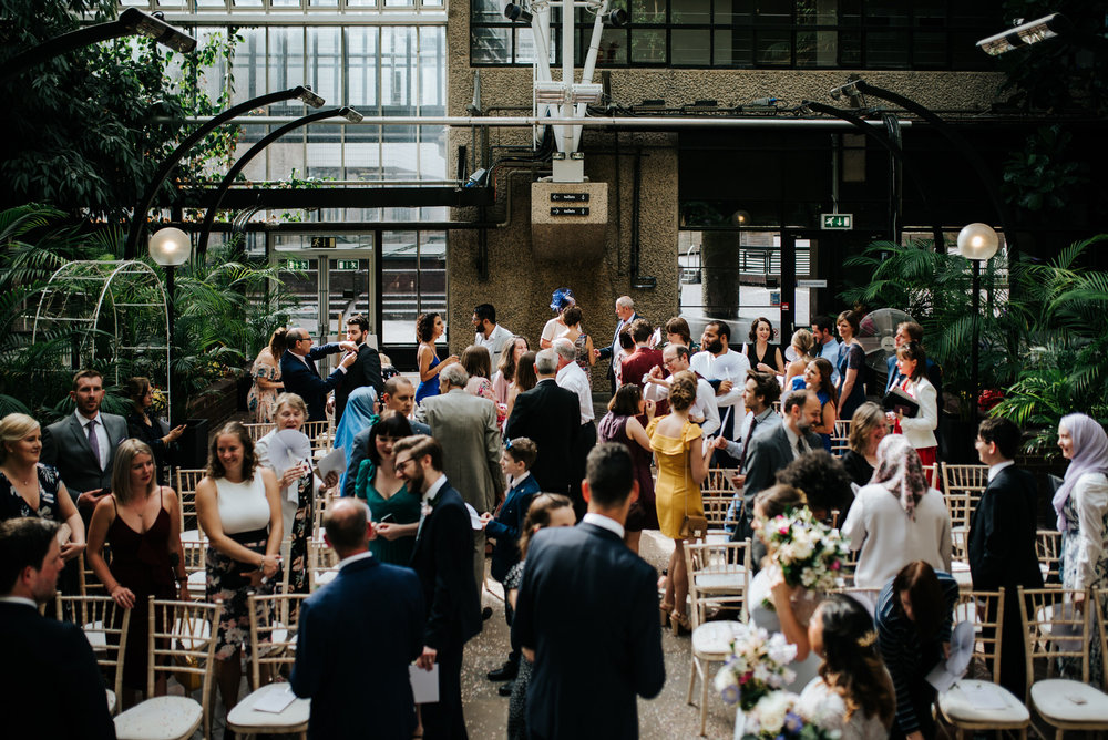 Wide photograph of guests mingling inside barbican wedding venue