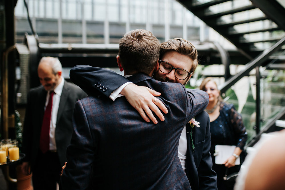 Groom and groomsman hug and embrace each other after wedding cer
