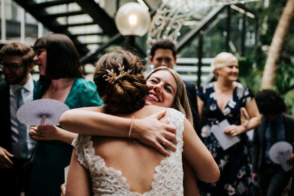 Bride and close friend hug each other and smile after wedding ce