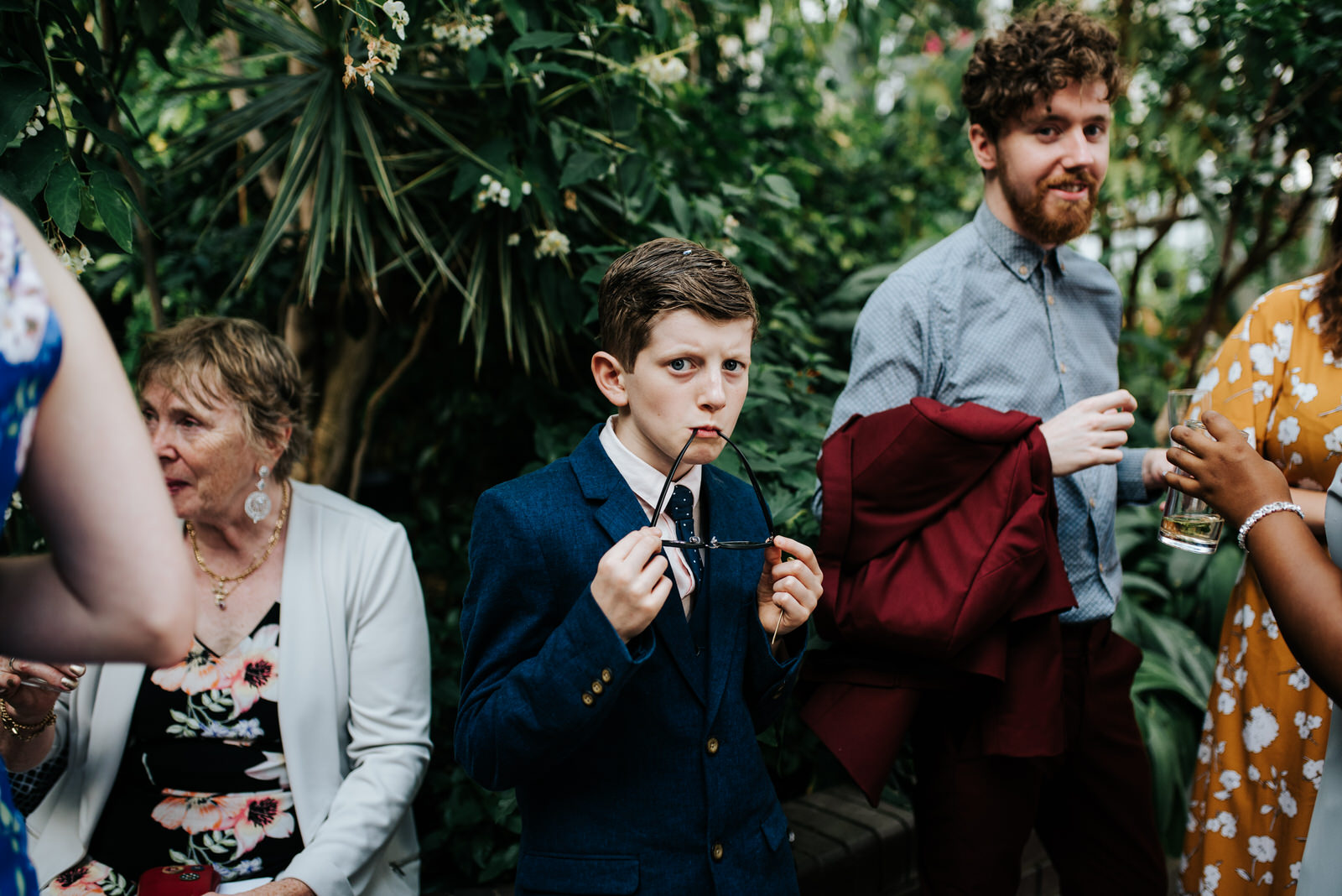 Young guest pulls funny face while resting the legs of his glass
