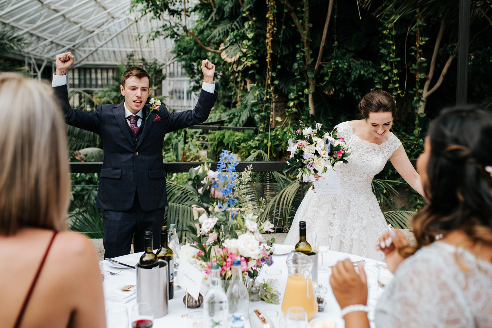Groom cheers as he and his wife arrive at their table in order to sit down