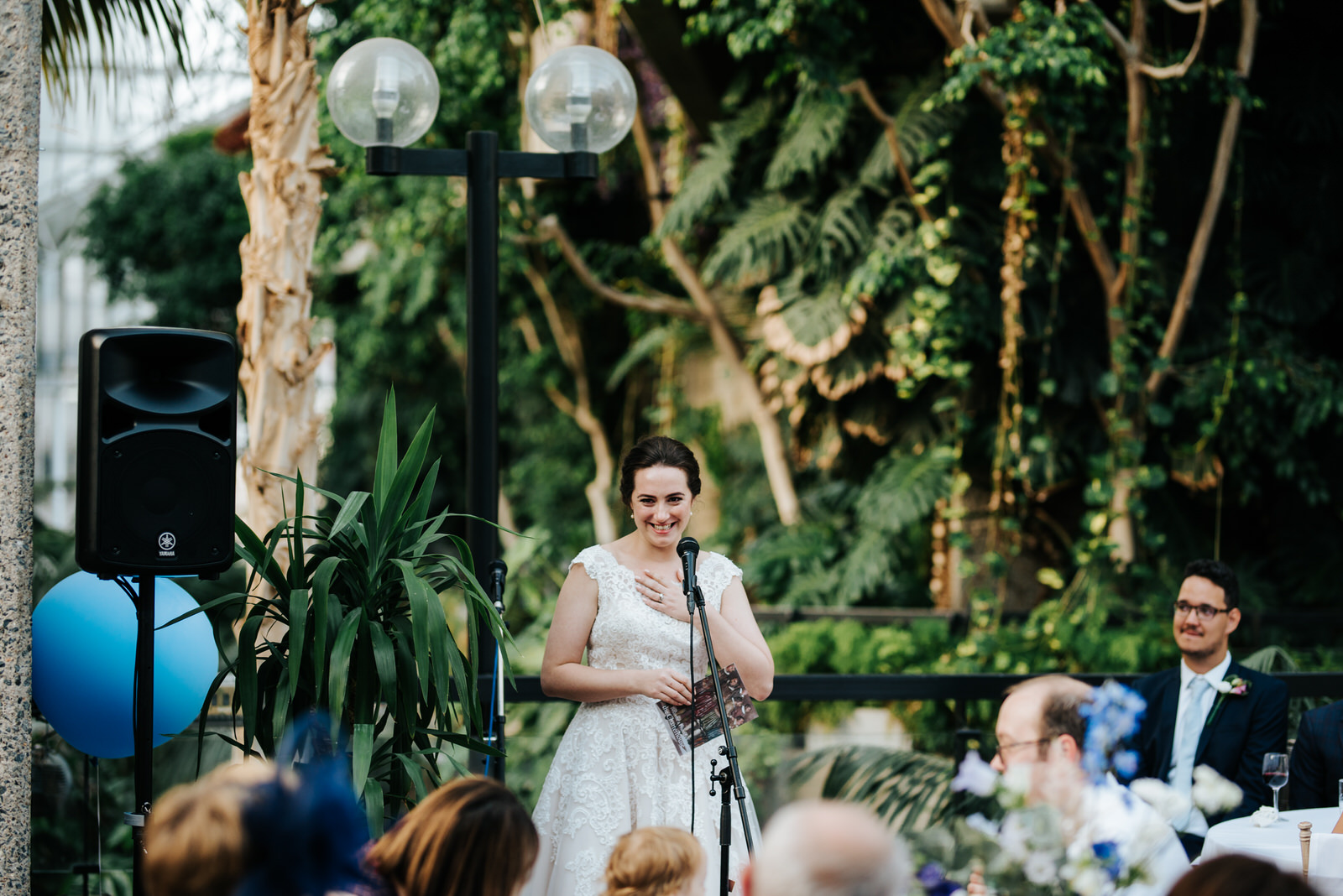 Bride holds one hand to her chest and smiles as she is about to