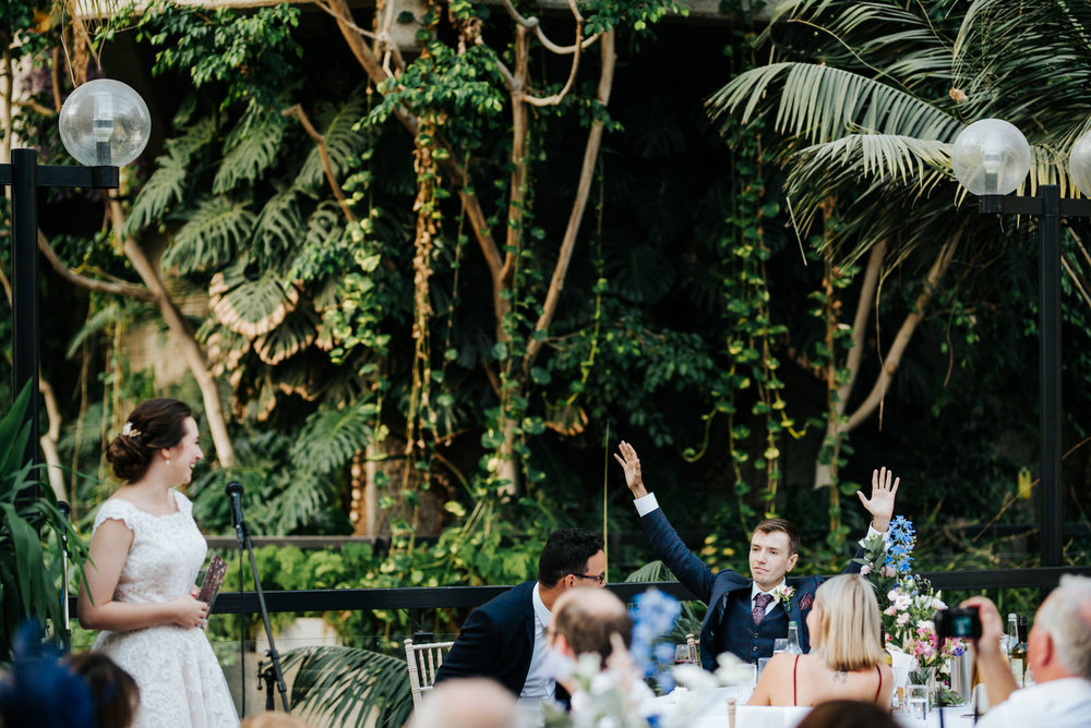 Groom raises both hands towards the air in celebratory gesture a