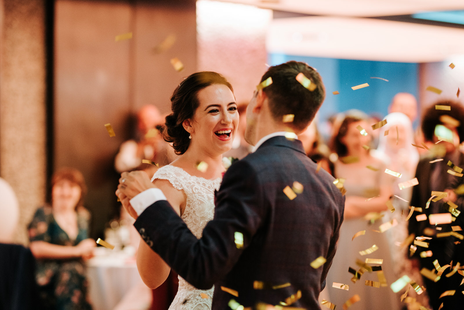 Bride smiles at groom as confetti falls during the end of their
