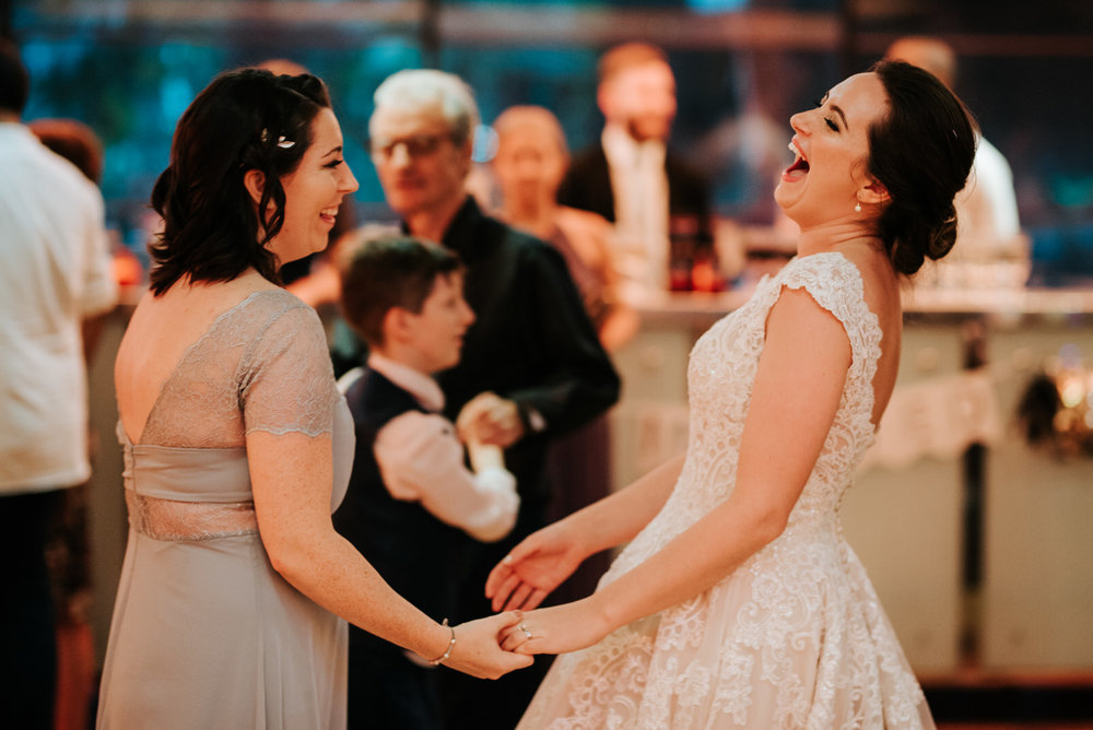 Bride and close friend share a laugh while dancing