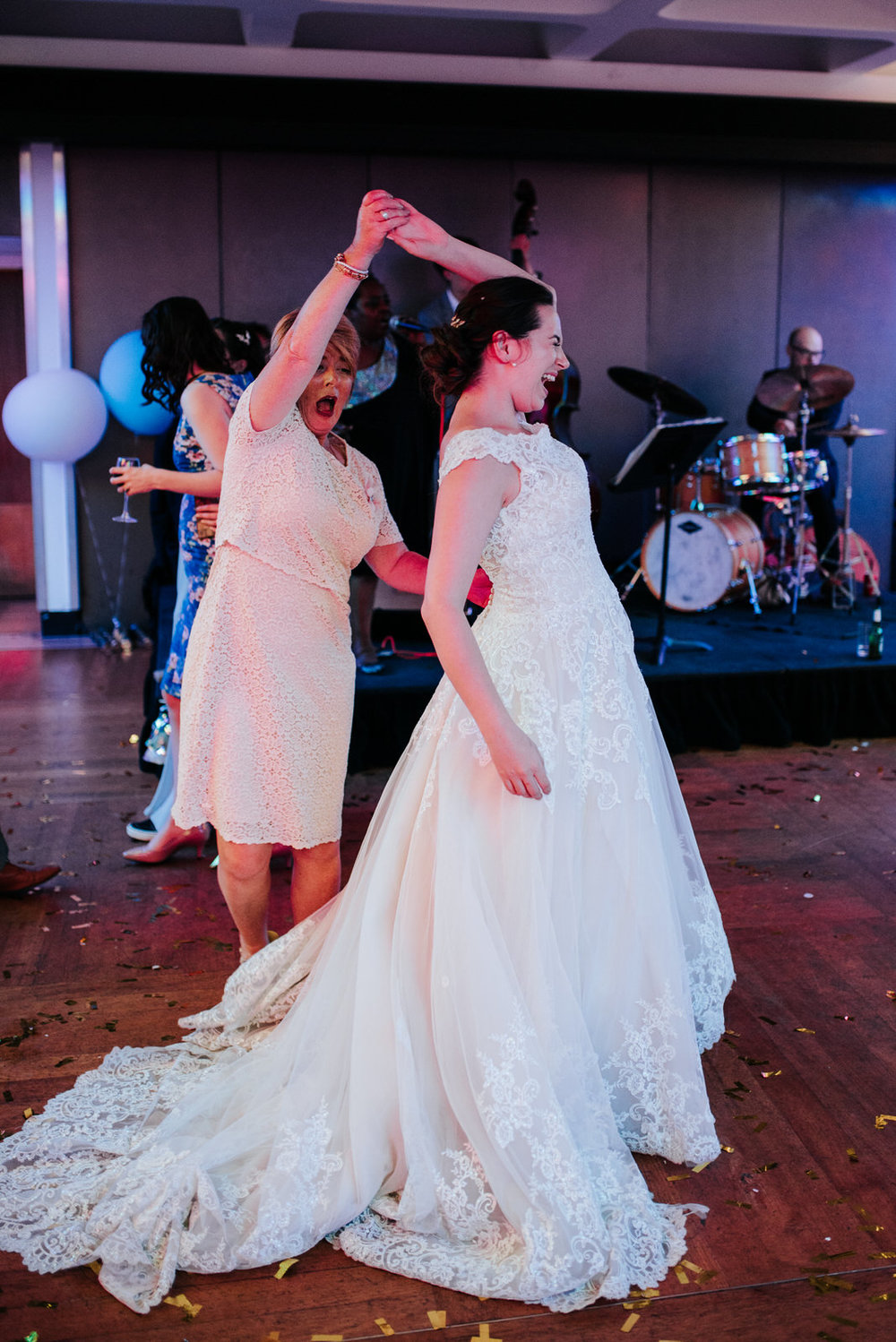 Bride laughs loudly as her auntie makes her do a twirl on the da