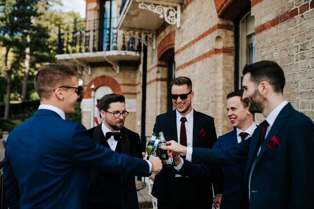 Group shot of groomsmen as they have a drink and toast before ceremony