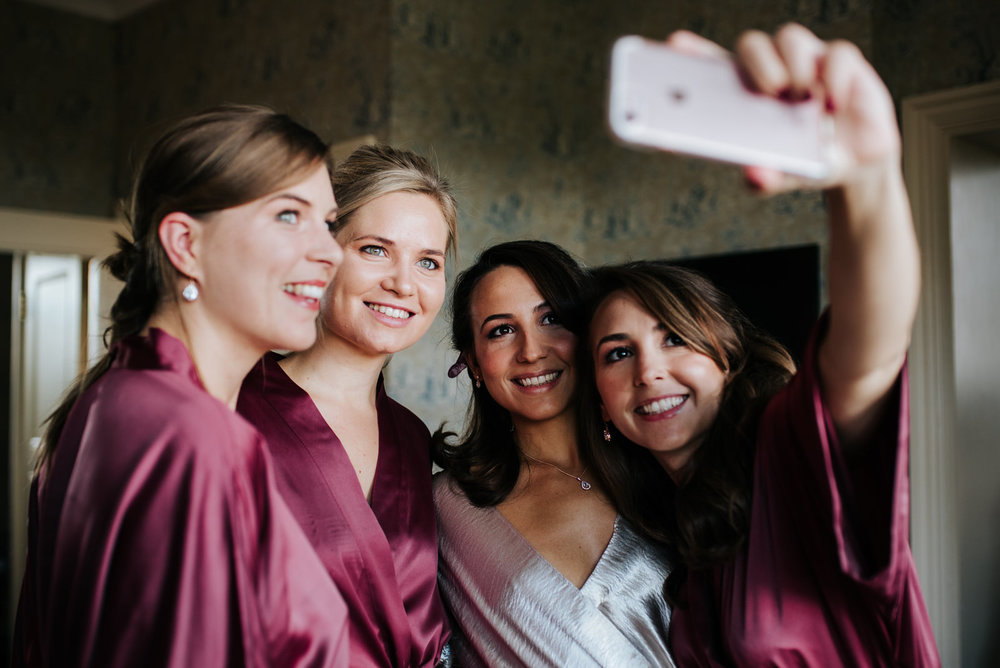 Bride and bridesmaids take a selfie in wedding robes
