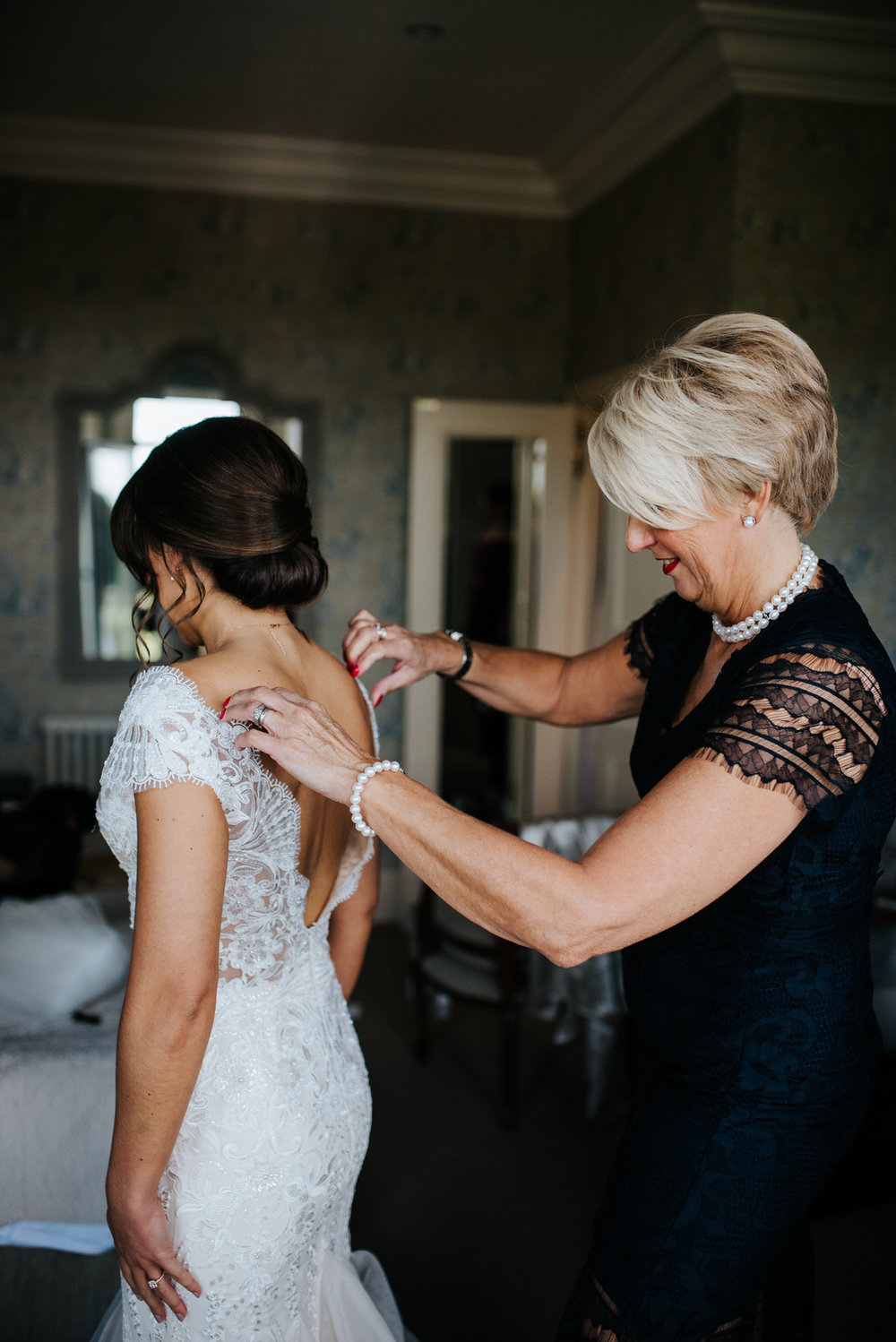 Bride's mom helps bride put on wedding dress