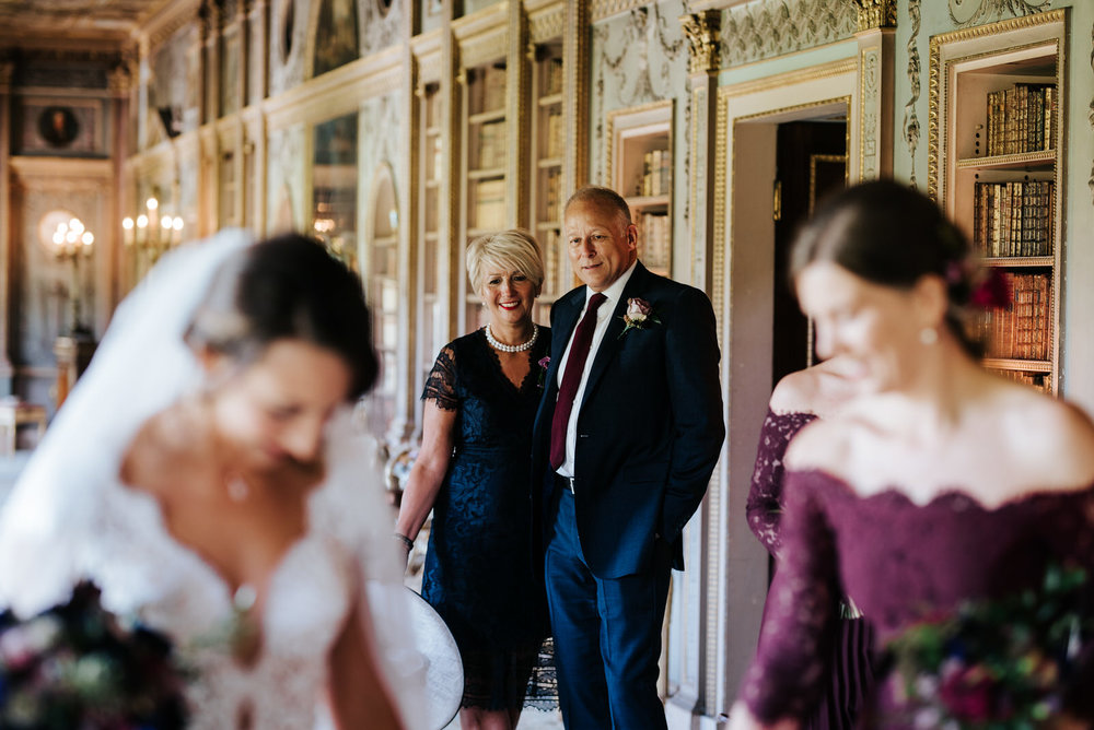 Bride's mum and step-dad look lovingly at bride and admire her
