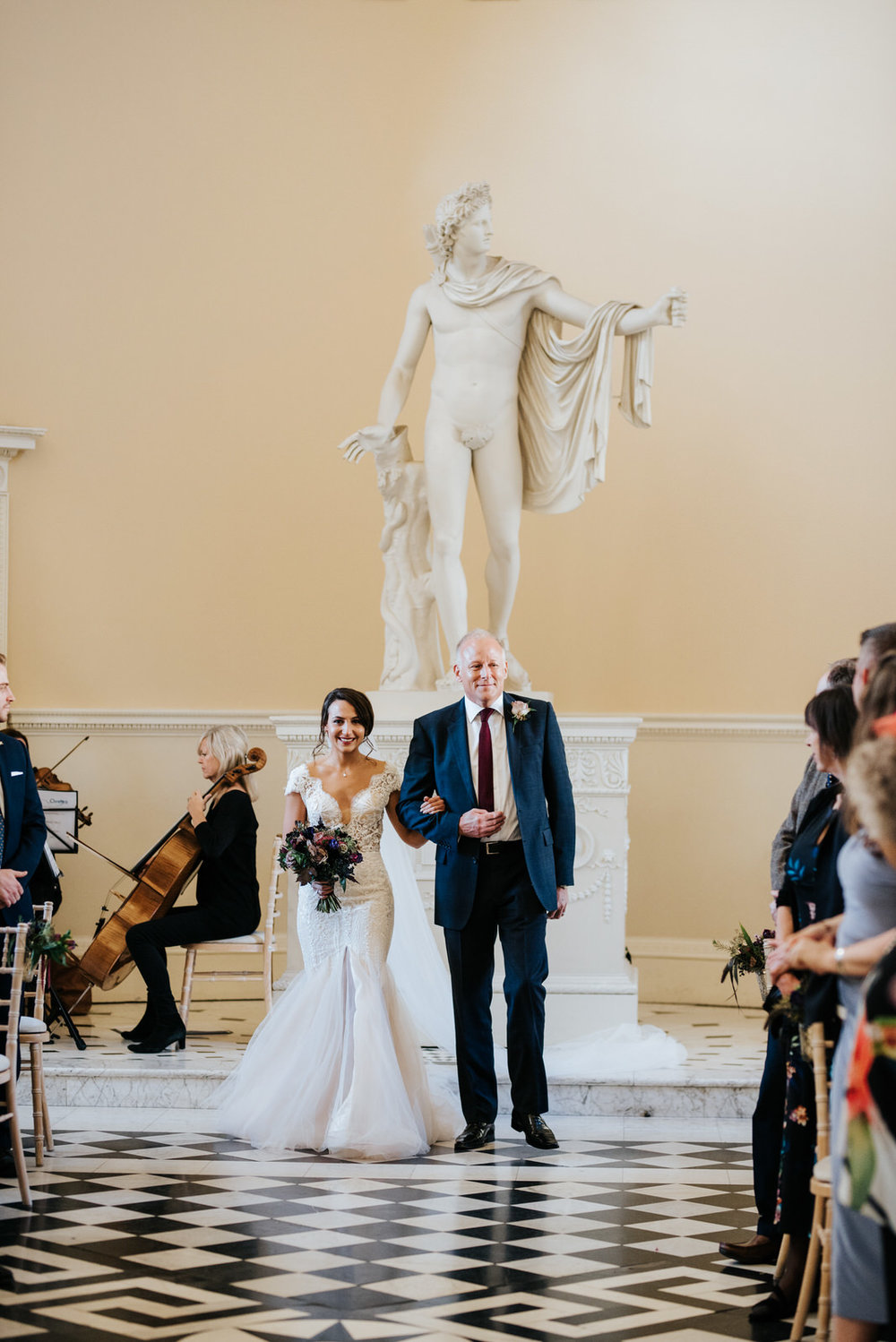 Bride and step-dad walk down the aisle as people smile