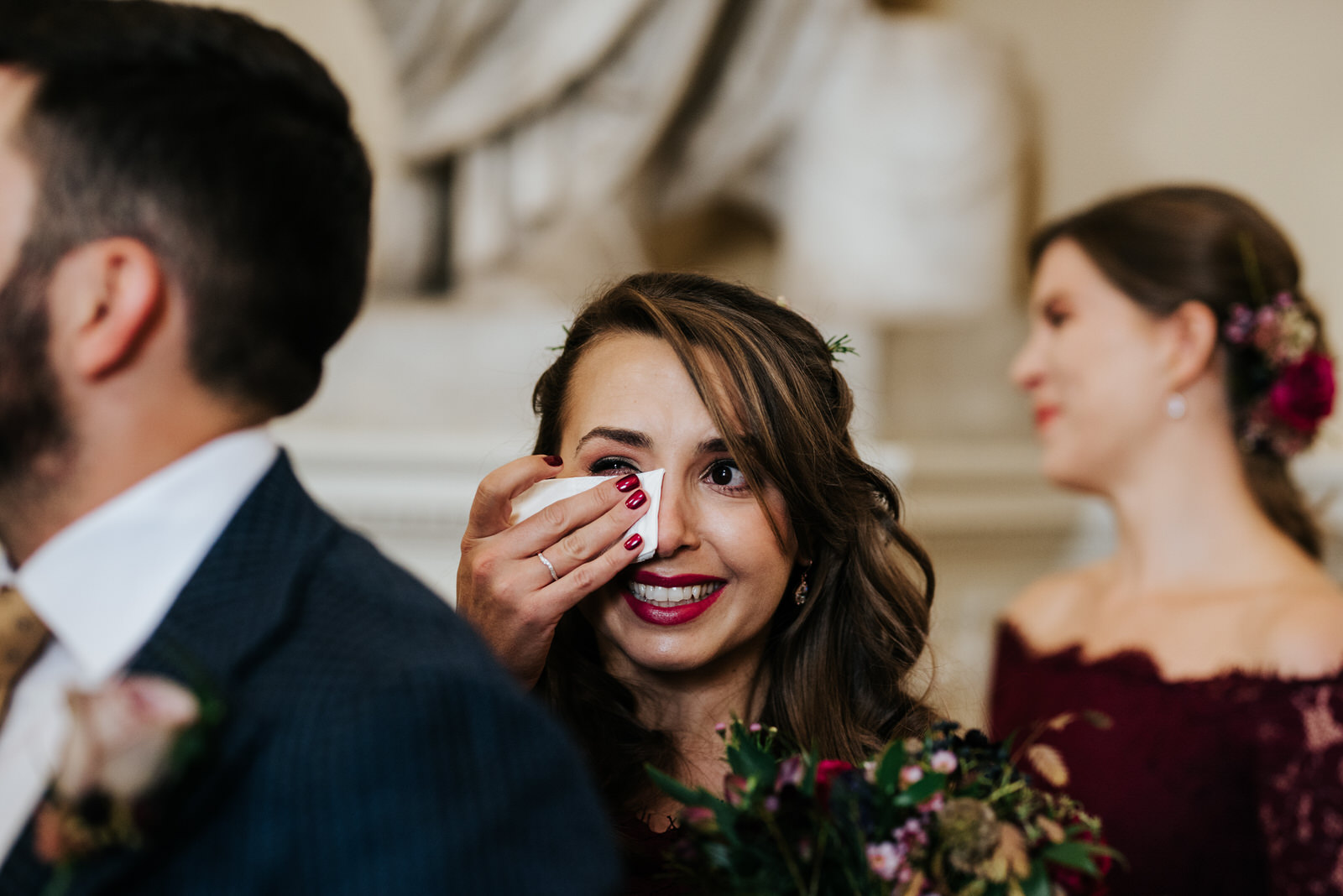 Bride's sister smiles and cries as bride walks down the aisle