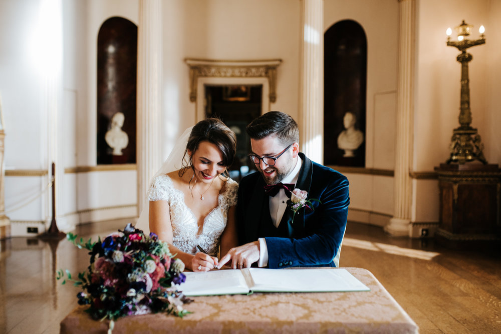 Bride and groom look extremely happy as they sit and sign wedding register
