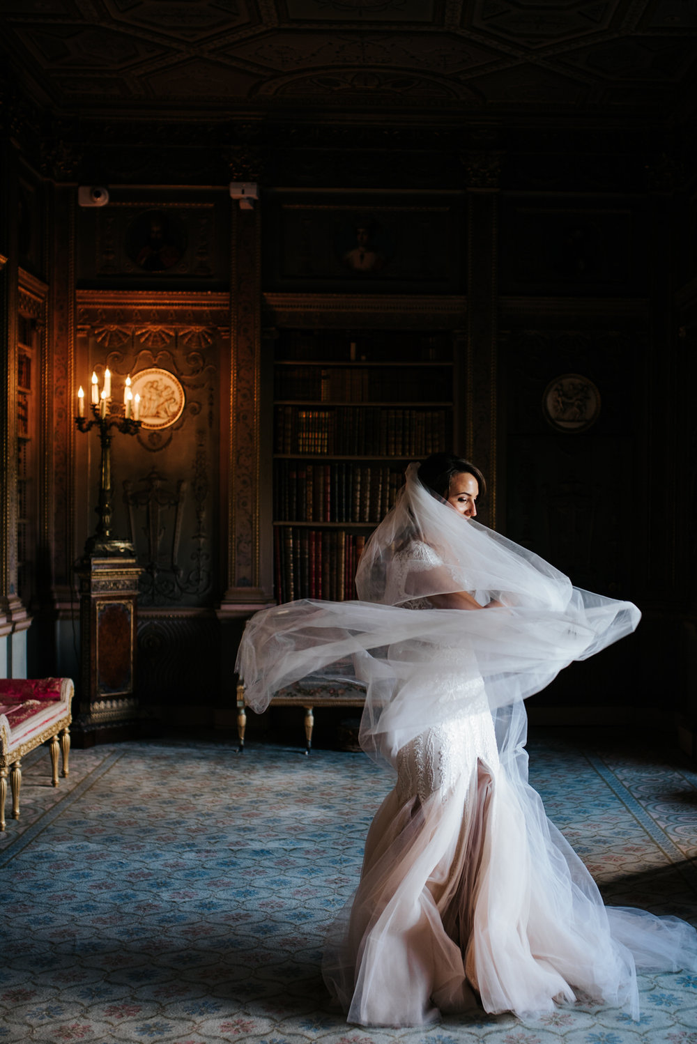 Bride twirls in her stunning dress and veil as light comes in from window