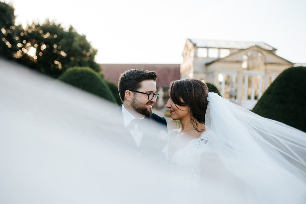 Romantic photo of bride and groom looking at each other while her veil floats in front of camera