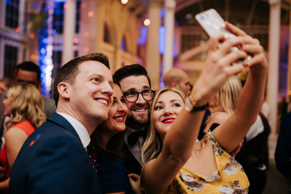 Guests take wedding selfie with groom