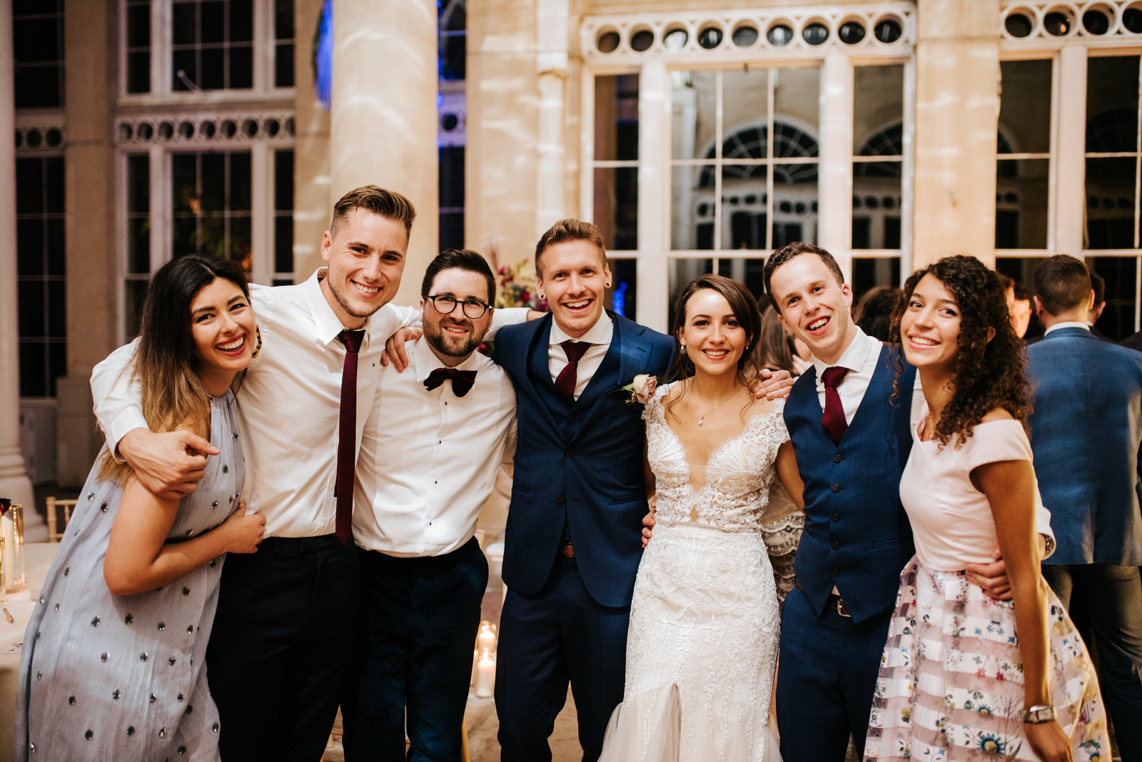 Group photo of bride, groom and guests looking at camera