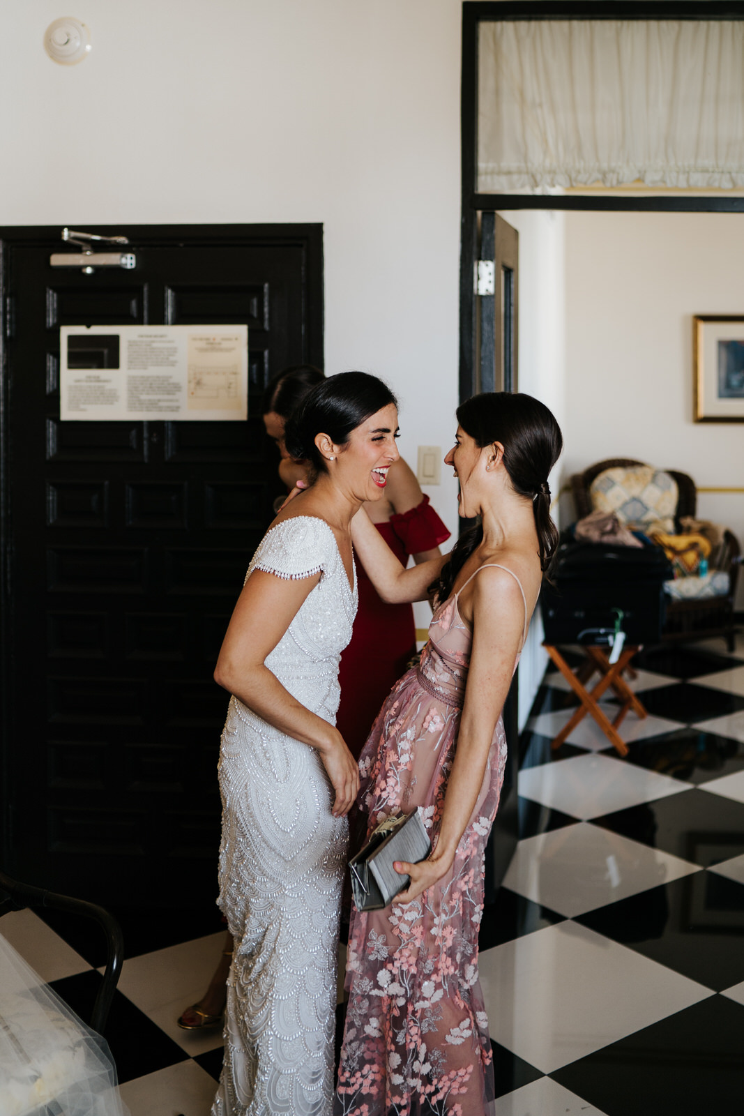 Bride and one of her best friends look at each other and smile after one of them drops something