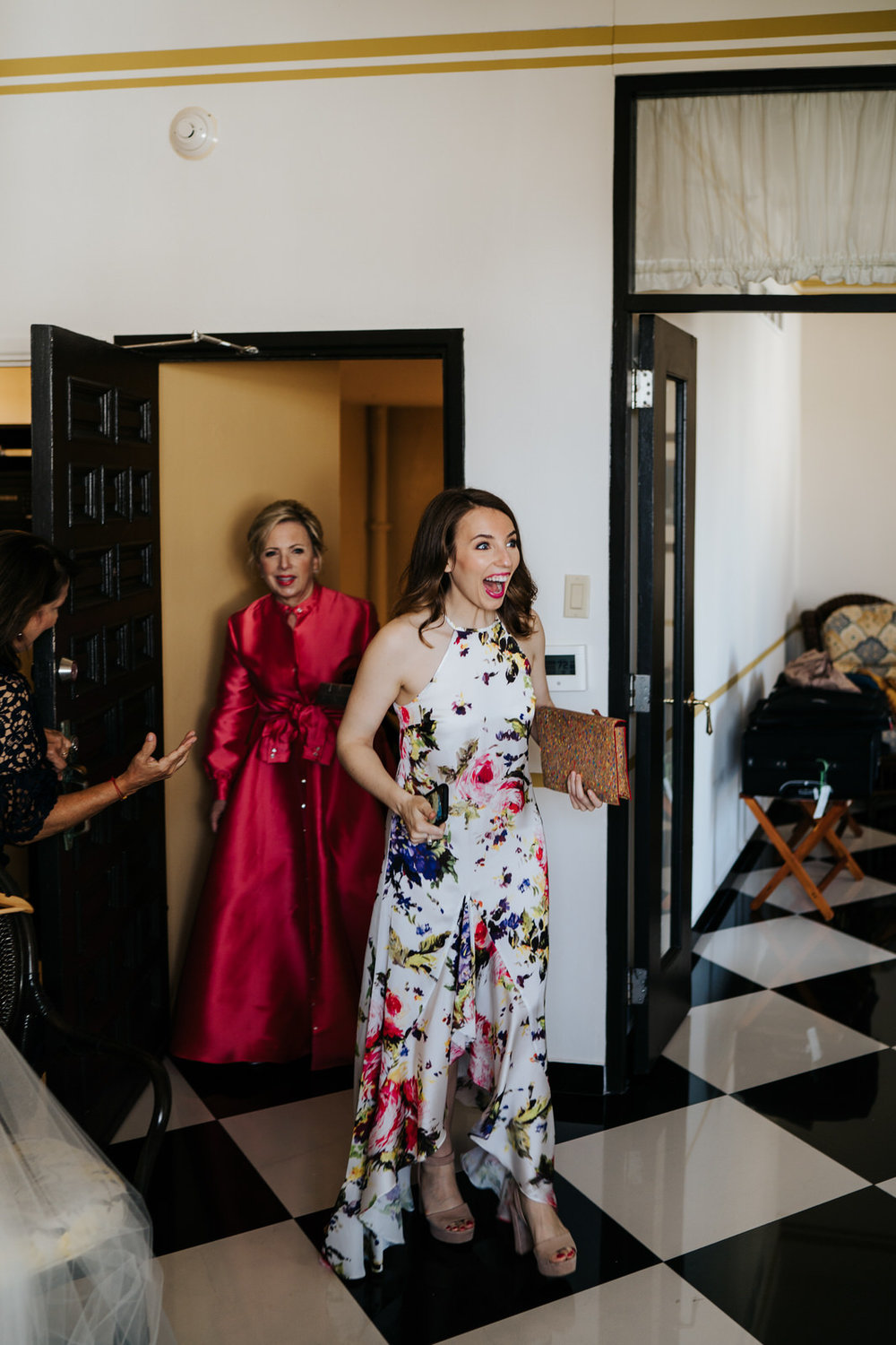  Groom's sister and mother enter the room where bride is getting ready for wedding and smile in shock when they see her 