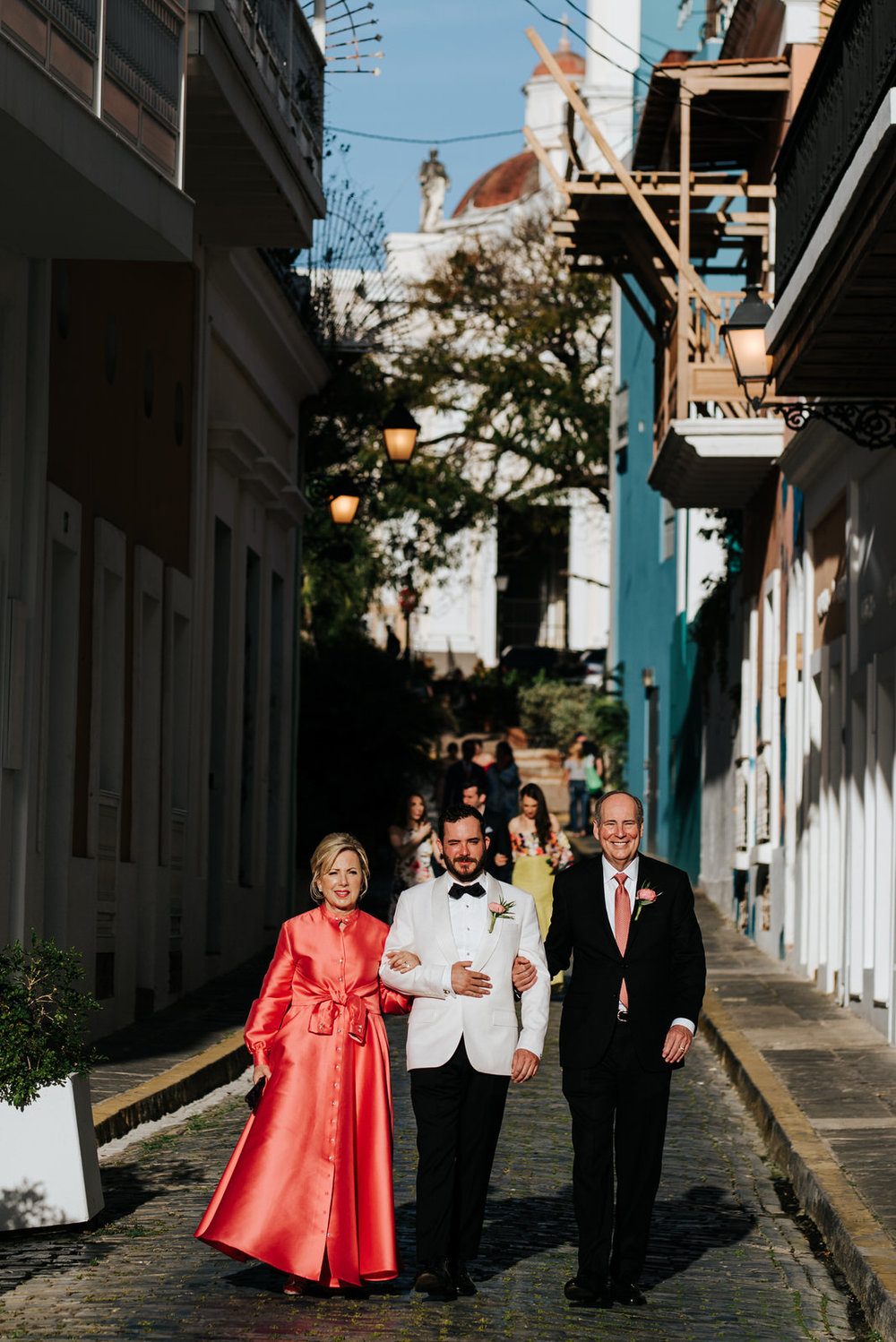  Groom and his parents walk down the streets of old san juan towards the wedding aisle 