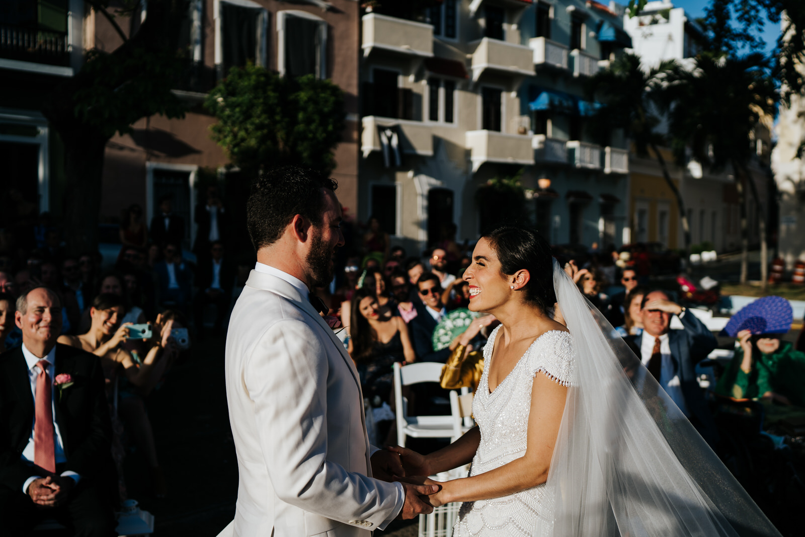 Seconds before the first kiss, the bride is holding hands with the groom and grinning with incredible joy