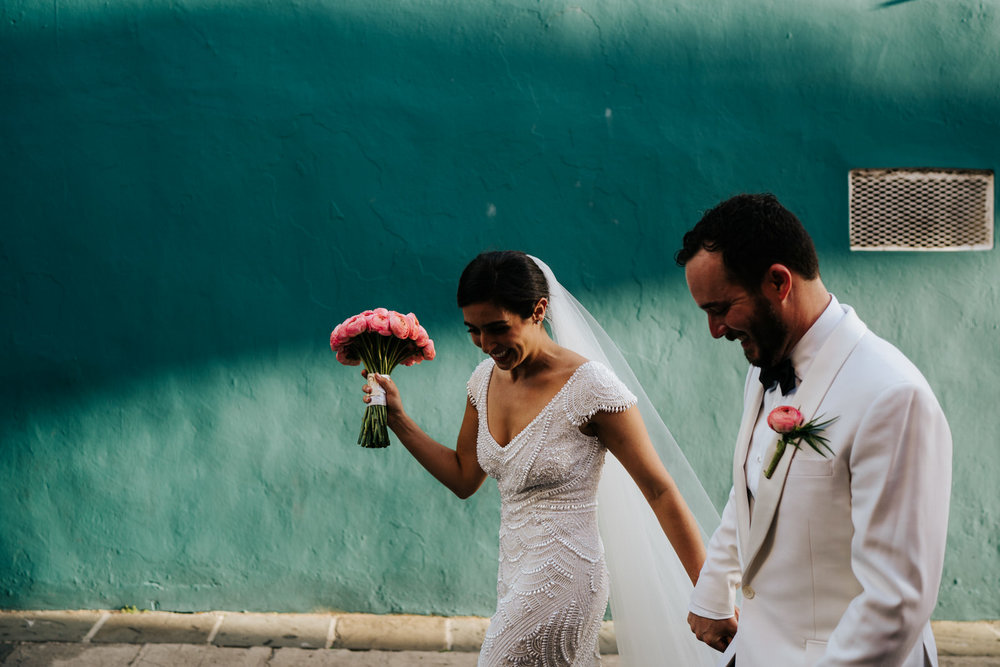  Bride and groom hold hands as they walk in front of turquoise wall in Old San Juan Puerto Rico 