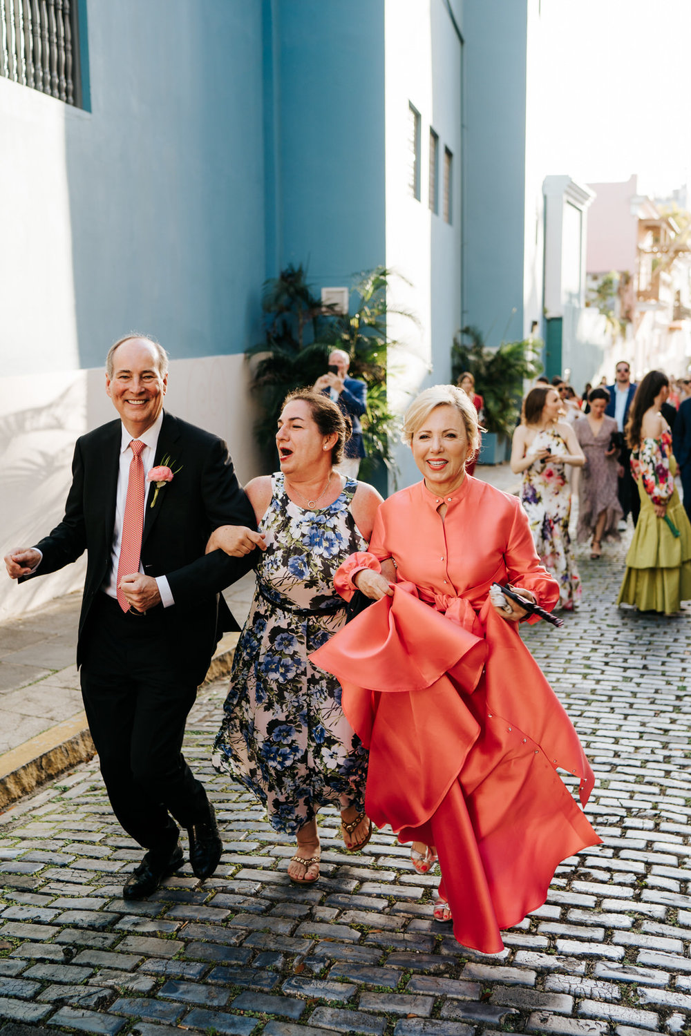  Groom's parents and a friend seen dancing and smiling as they walk towards the El Convento for the wedding reception 