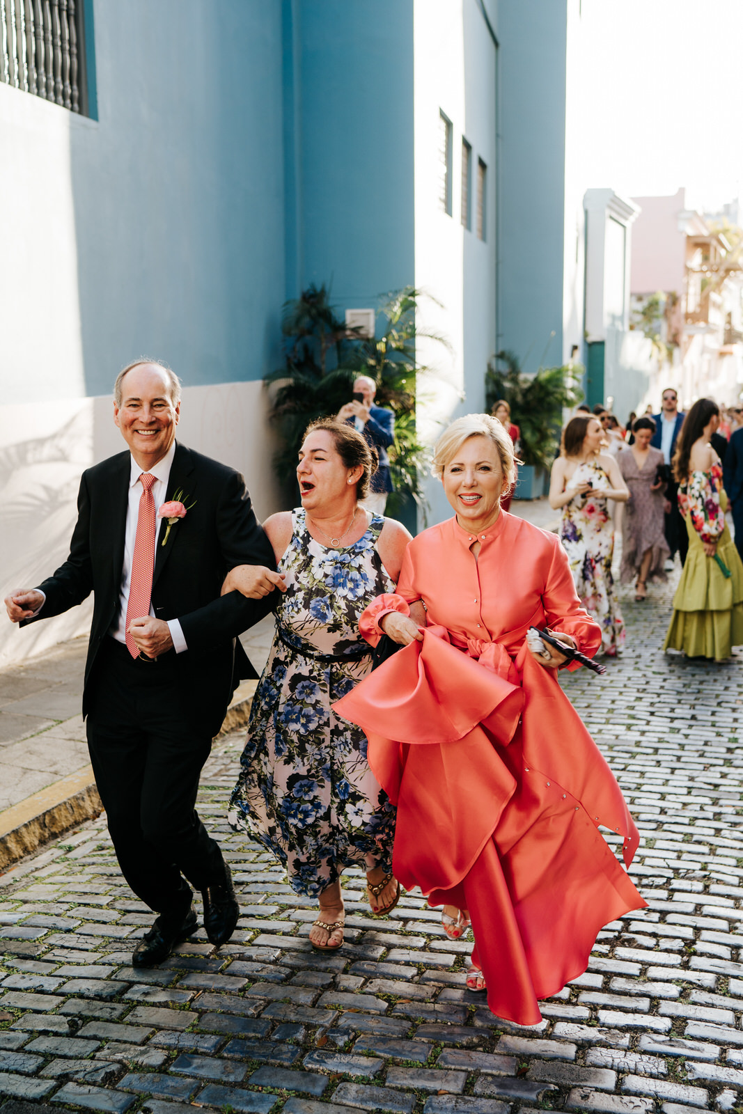 Groom's parents and a friend seen dancing and smiling as they walk towards the El Convento for the wedding reception