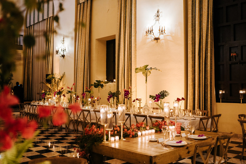  Wide photograph of the decoration in the Hotel El Convento wedding room accentuated with green leaves and red flowers 