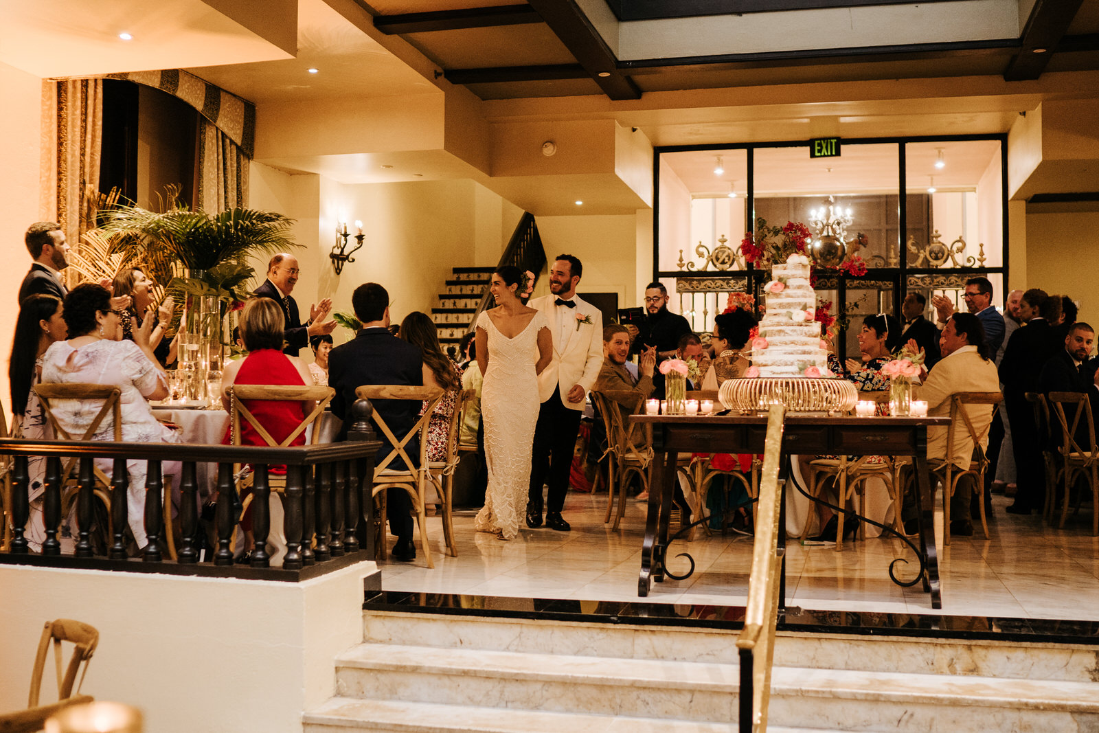 Bride and groom make their entrance into the wedding reception room as everyone stands and claps
