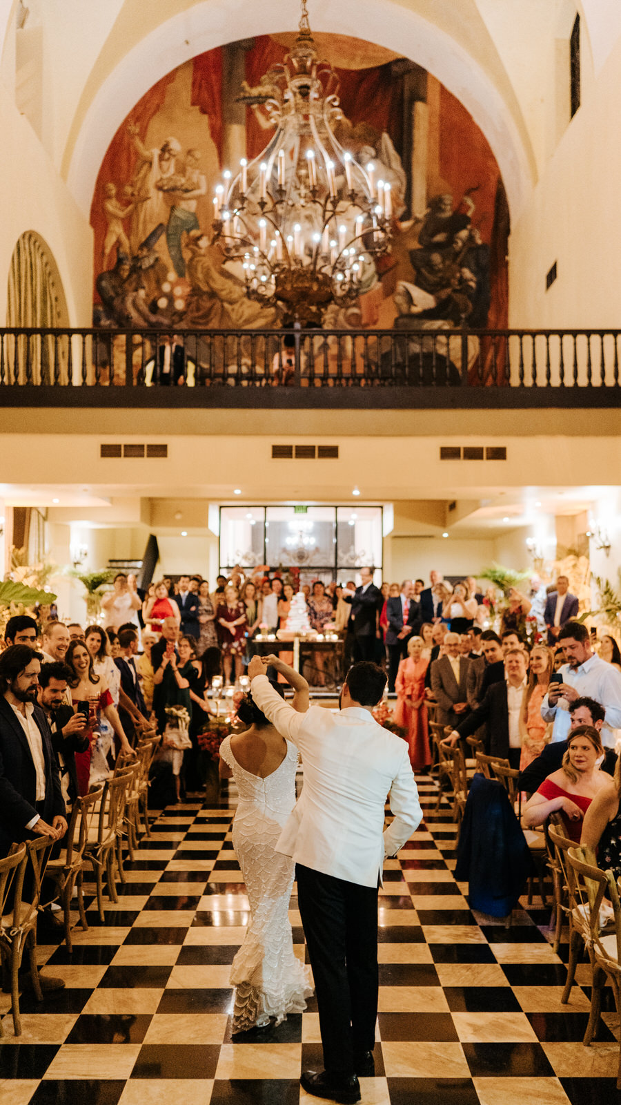 Vertical photograph of bride and groom during their first dance while groom makes bride do a twirl