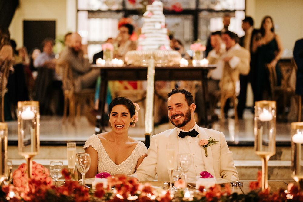  Bride and groom are sitting at their wedding table and smile during the speeches 