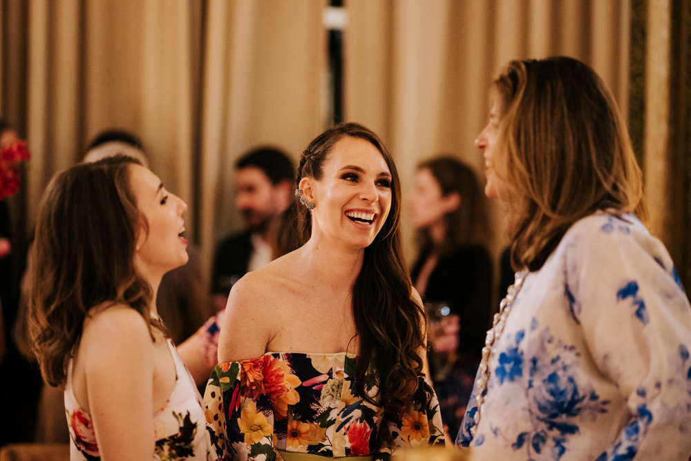  Candid photograph of groom's sisters talking to a friend and smiling 