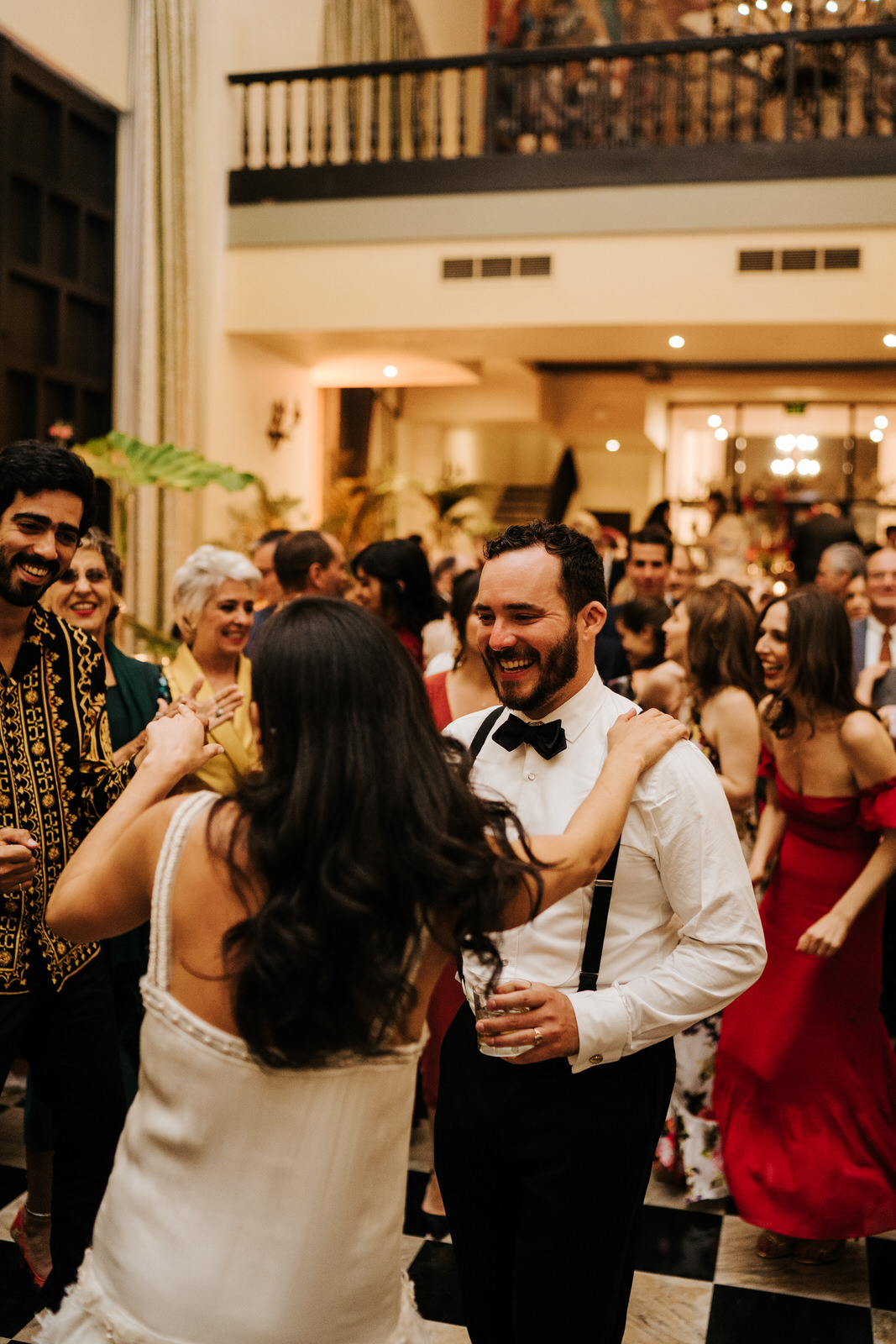 Bride holds groom's shoulder on the dancefloor while he smiles at her