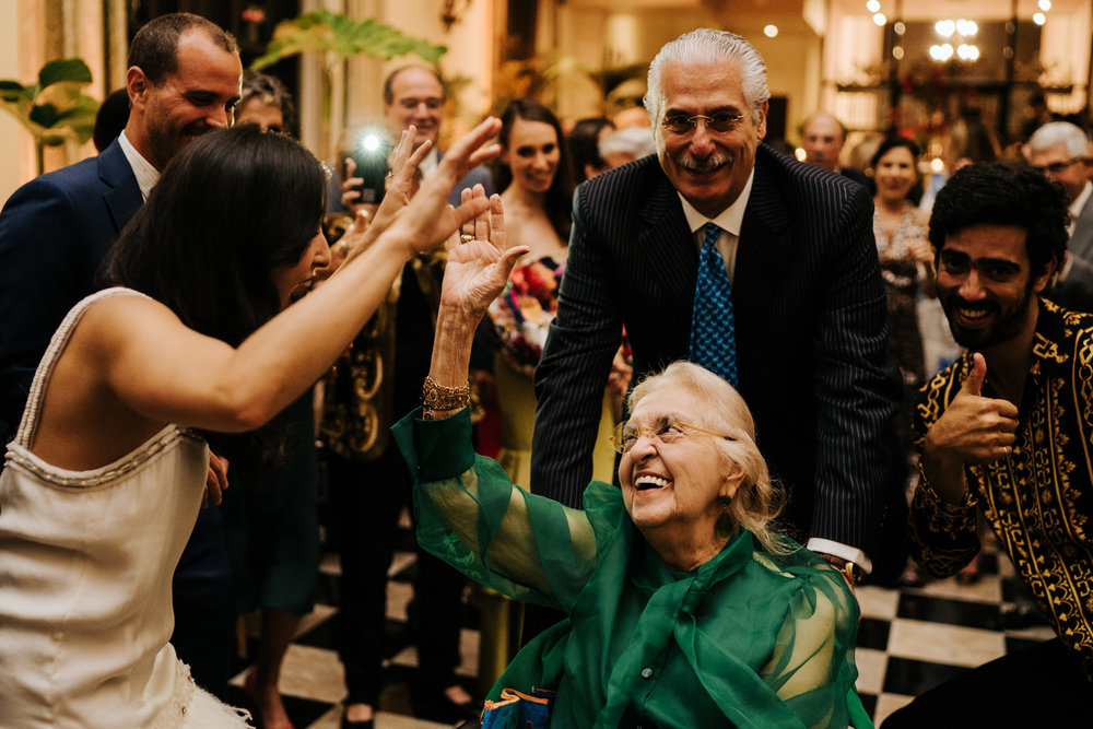  Bride's grandmother is on the dancefloor in her wheelchair and smiling as everyone encourages her and bride smiles at her 