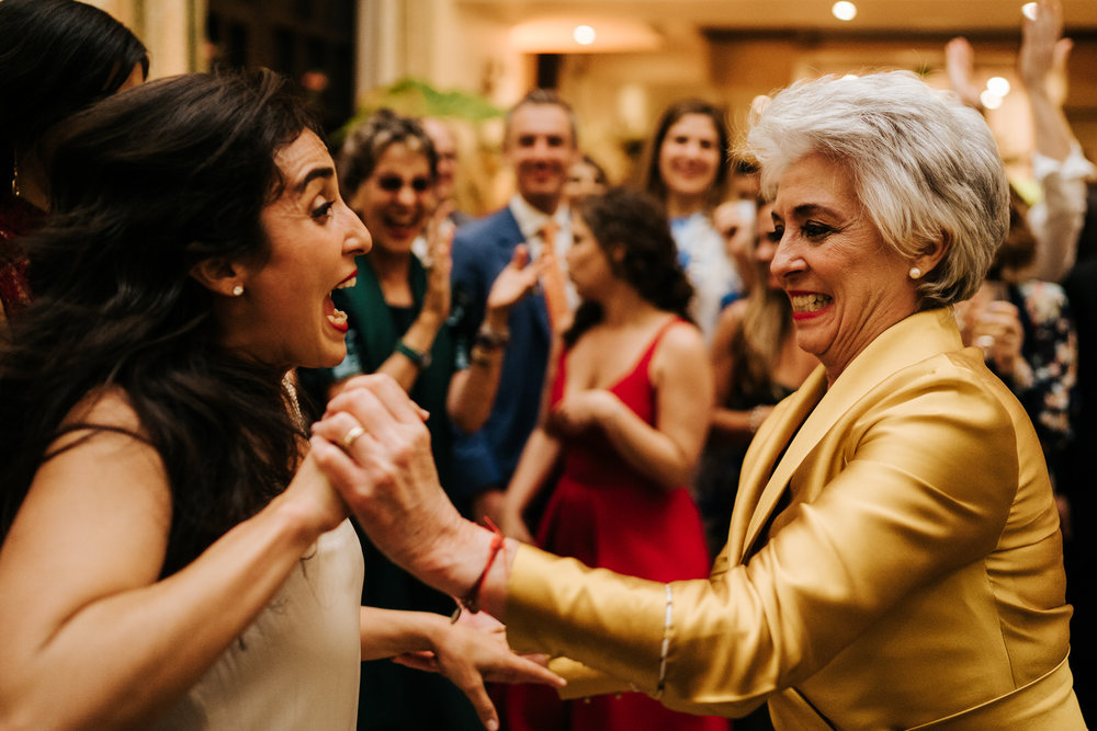  Bride and her mother having a fantastic time as they hold hands and dance on the dancefloor 