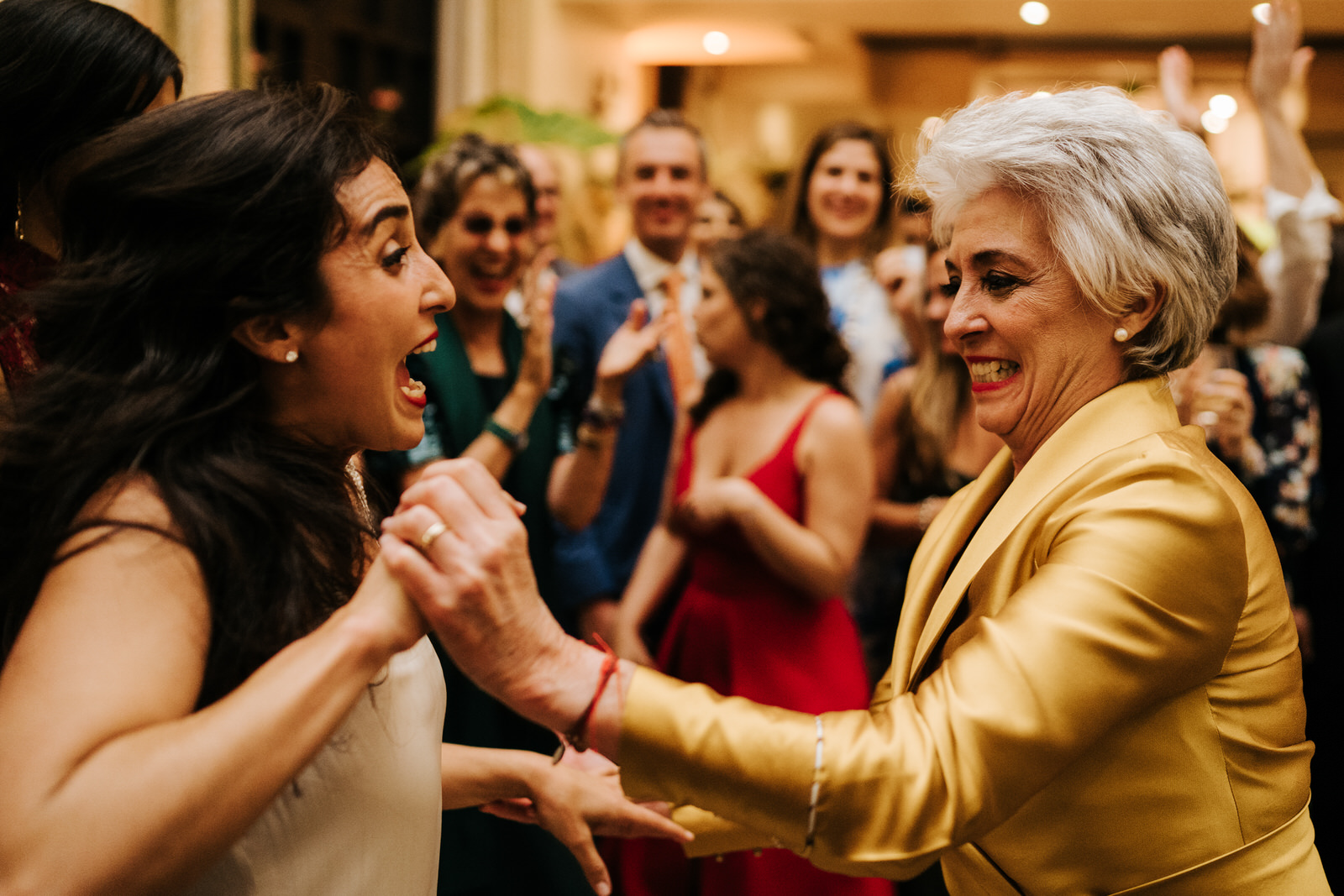 Bride and her mother having a fantastic time as they hold hands and dance on the dancefloor