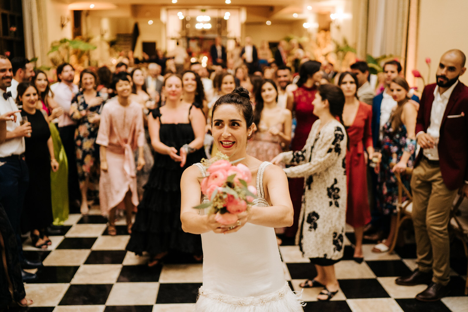 Bride holds her bouquet as her female friends stand behind her ready to catch it
