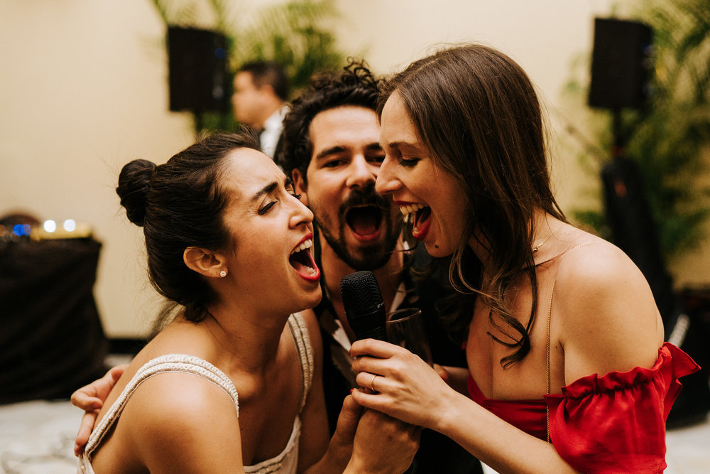 Bride and two friends hold the microphone and sing into it passionately 