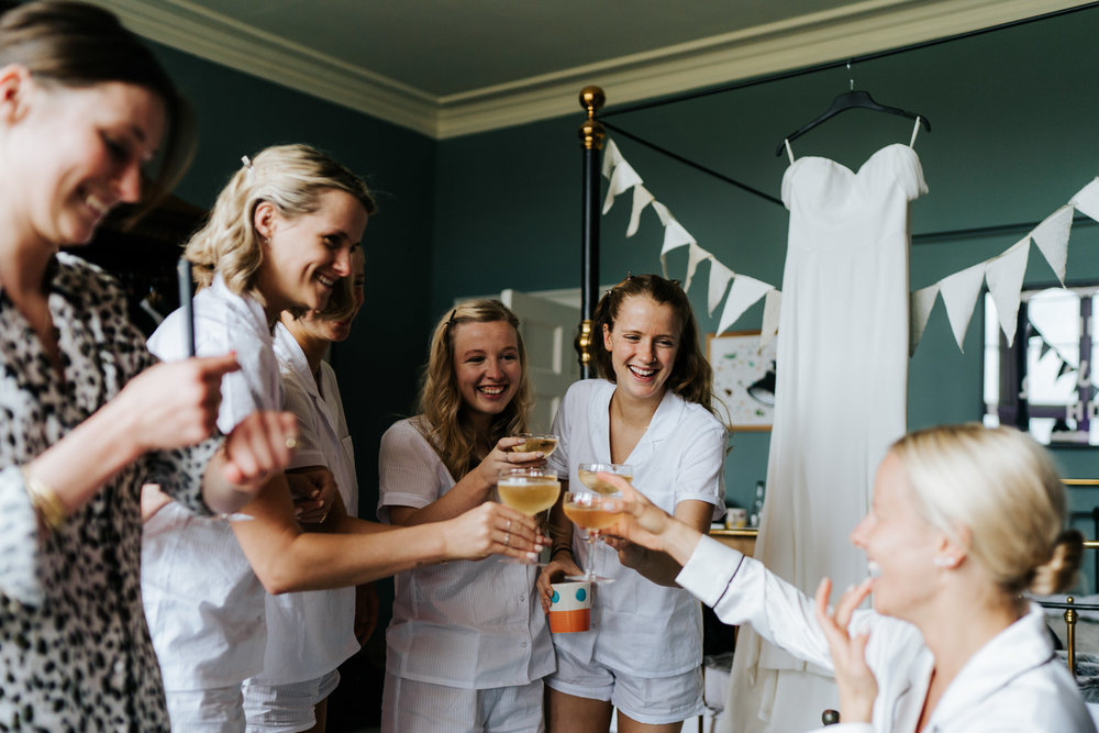  Bride and bridesmaids each hold a glass of champagne and say a toast for the day ahead 