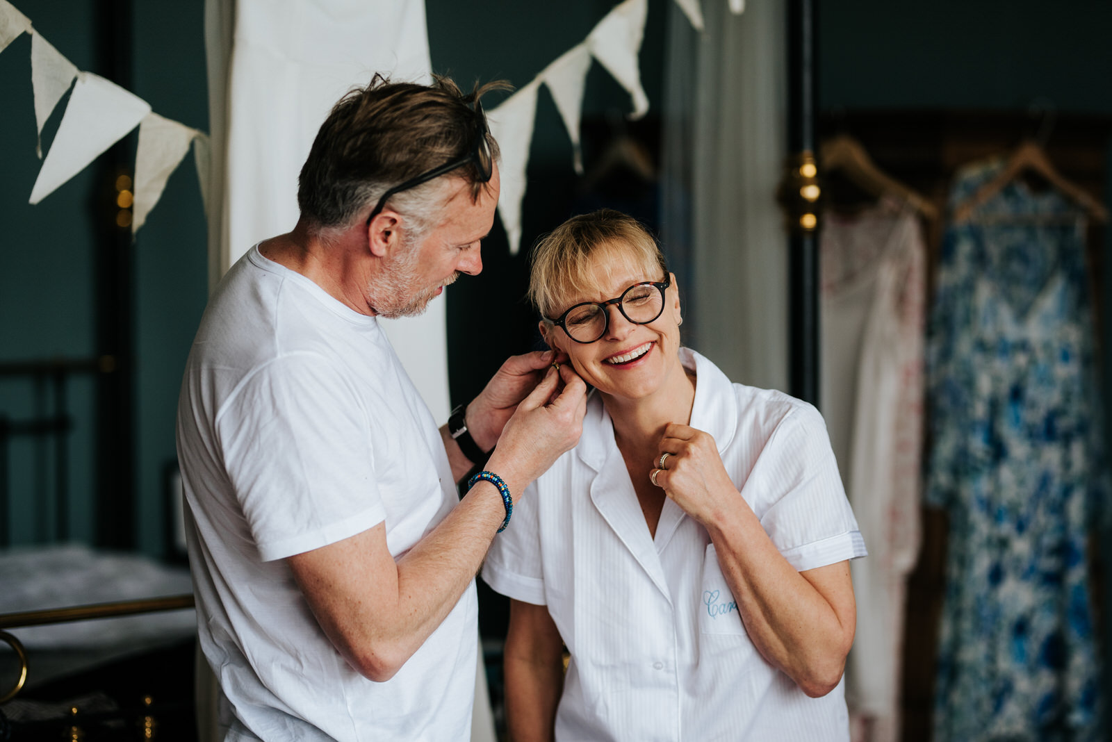 Bride's father helps bride's mother put on an earring