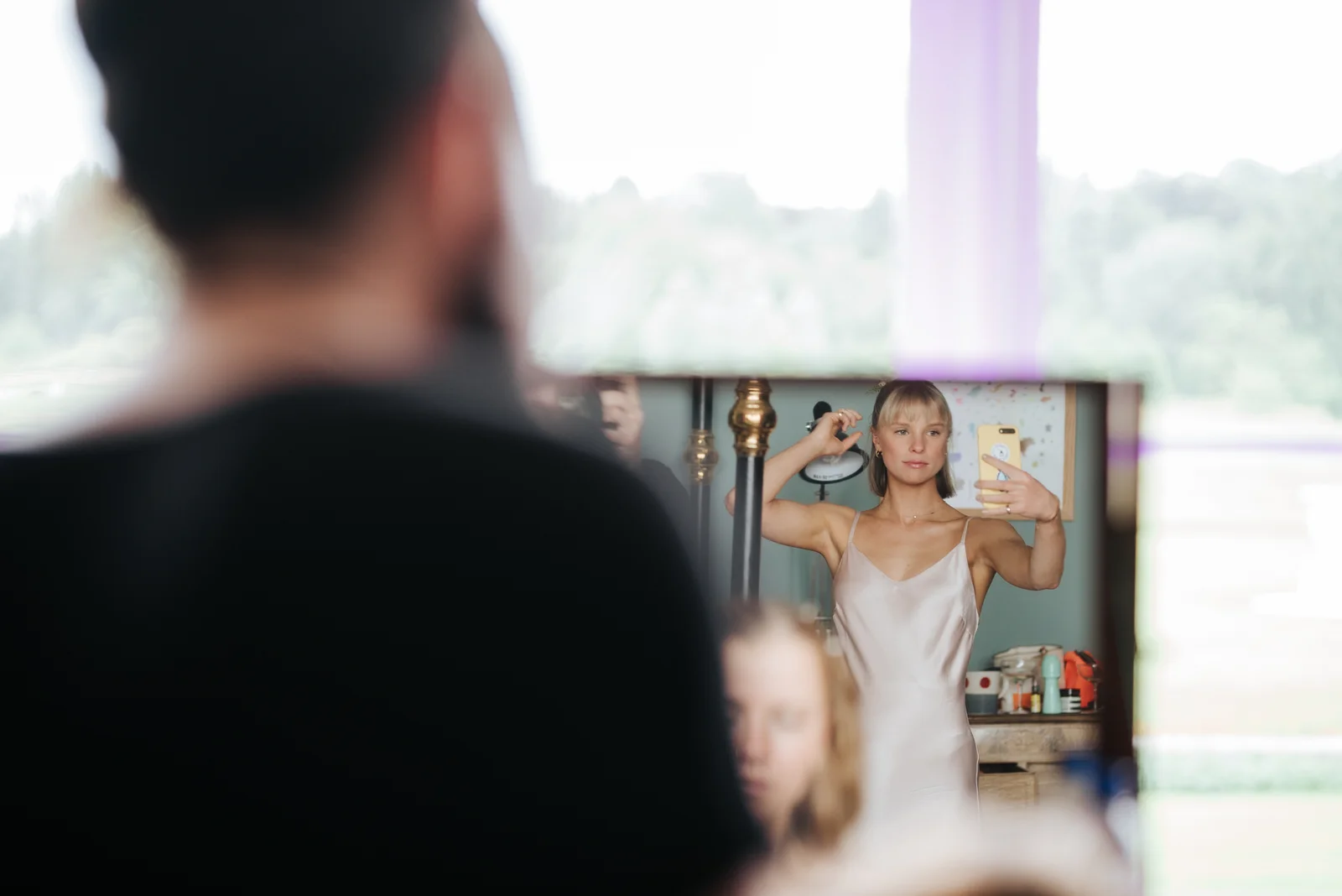 Other sister of the bride looks at herself in selfie camera and adjusts her hair